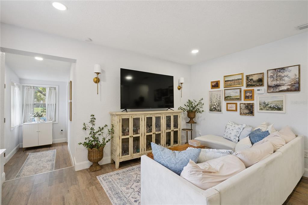 A living room features a television on a wooden cabinet, gallery wall, and sectional sofa — 1537 FAITH COURT, DELTONA, FL