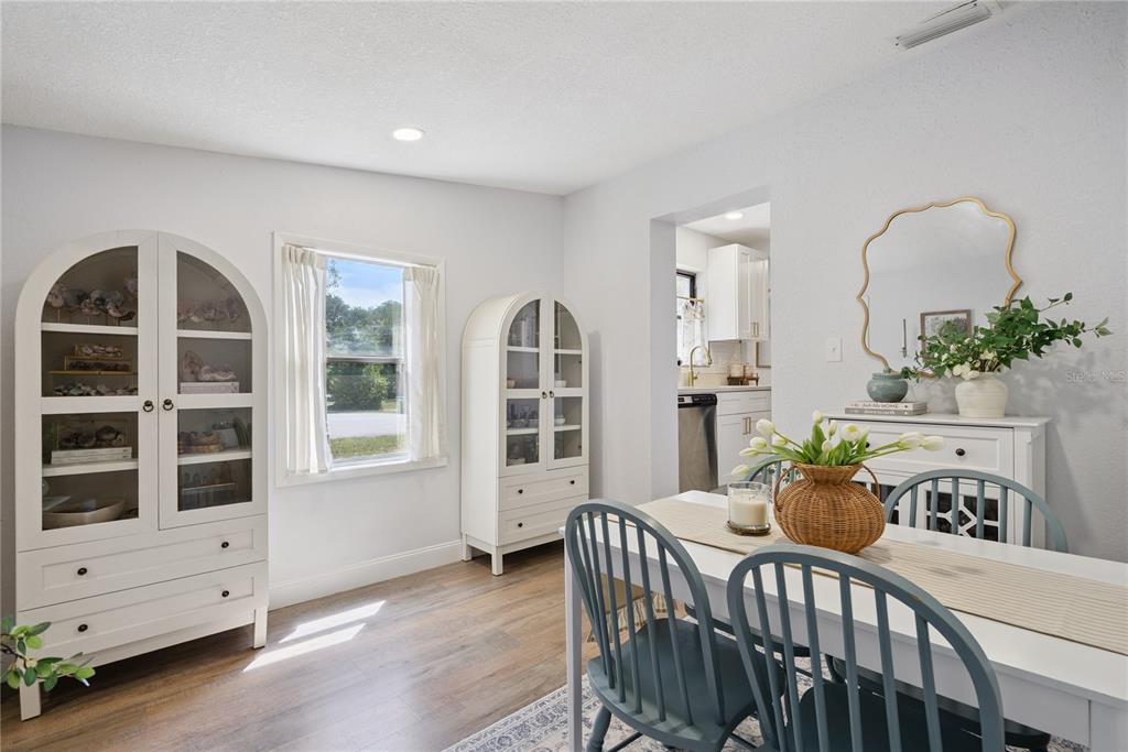 A dining room features a white table with blue chairs, two arched cabinets, and wood flooring — 1537 FAITH COURT, DELTONA, FL