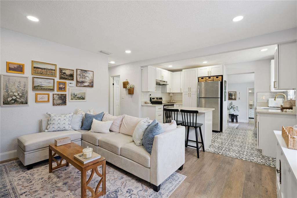 A living room with a sectional sofa opens into a kitchen with white cabinetry — 1537 FAITH COURT, DELTONA, FL