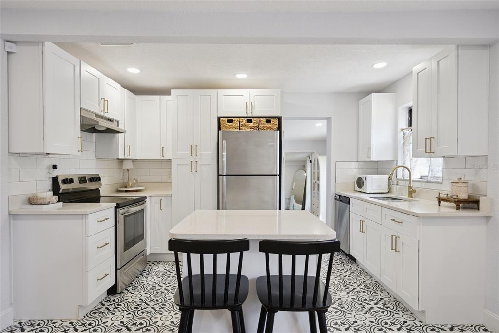 A kitchen features white cabinets, stainless steel appliances, a center island, and patterned floor tiles — 1537 FAITH COURT, DELTONA, FL