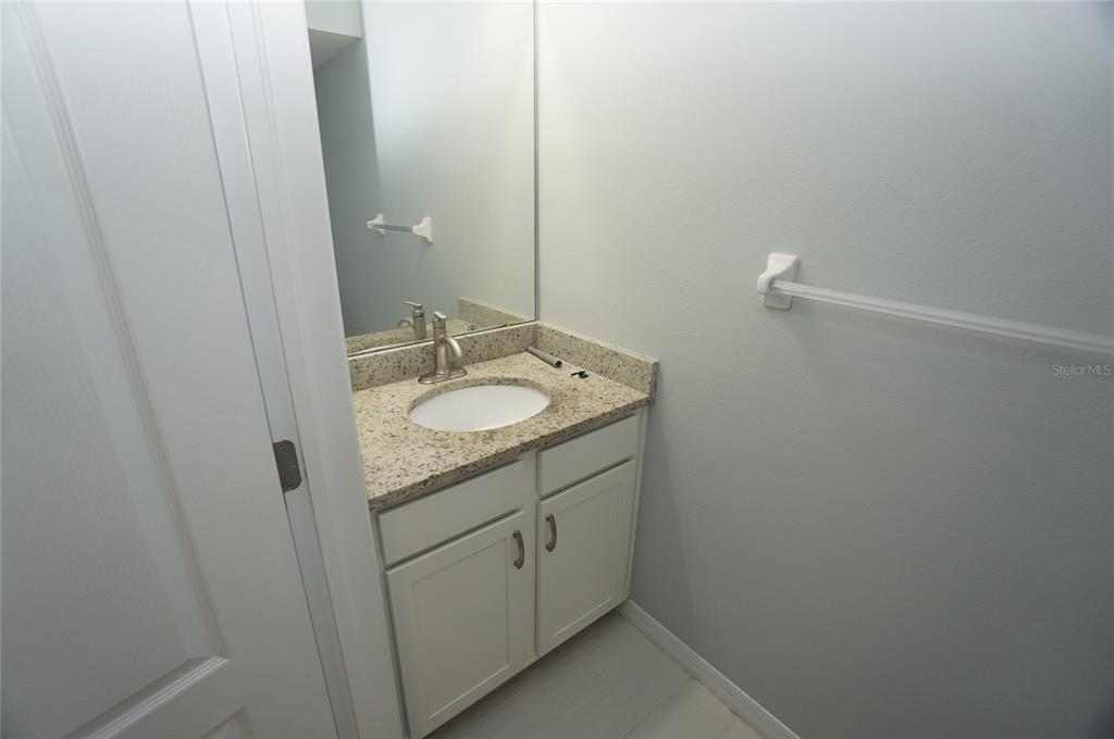 A bathroom vanity with a granite countertop, white cabinets, and a mirror on a wall — 7001 INTERBAY BOULEVARD UNIT 236, TAMPA, FL