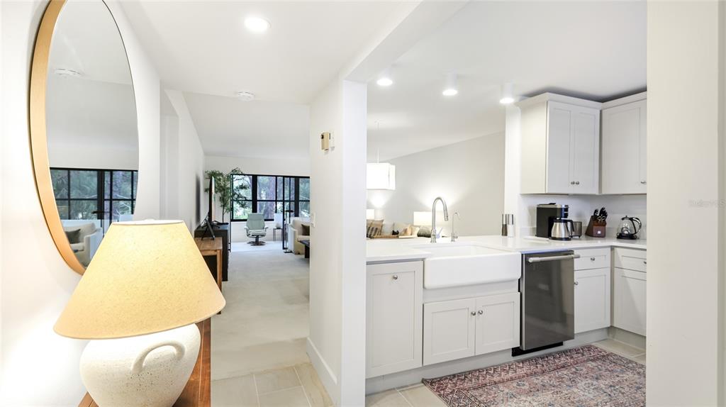 A kitchen with white cabinets and a farmhouse sink overlooks a living area — 303 SPRINGDALE DRIVE UNIT 303, BRADENTON, FL