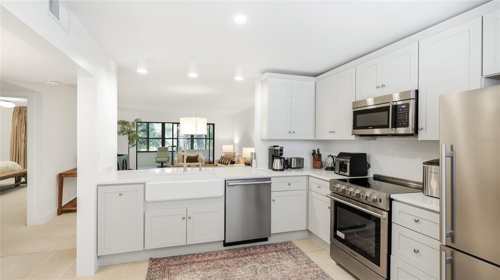 A modern kitchen features white cabinetry, stainless steel appliances, and a farmhouse sink — 303 SPRINGDALE DRIVE UNIT 303, BRADENTON, FL