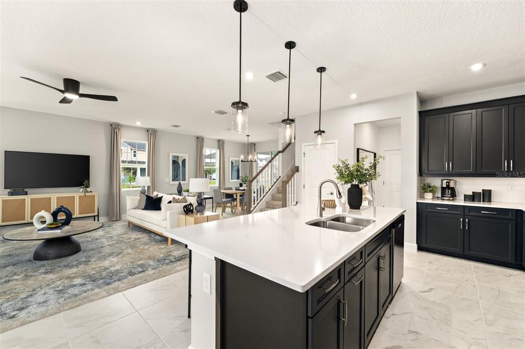 A kitchen island with a white countertop sits in an open-concept room with dark cabinetry — 416 BANANA PEPPER WAY, GROVELAND, FL