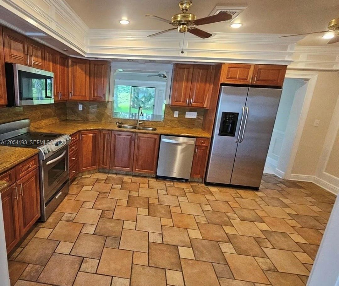 A kitchen with wood cabinets, granite countertops, stainless steel appliances, and tiled flooring — 4602 King Palm Dr, Tamarac FL 33319, TAMARAC, FL