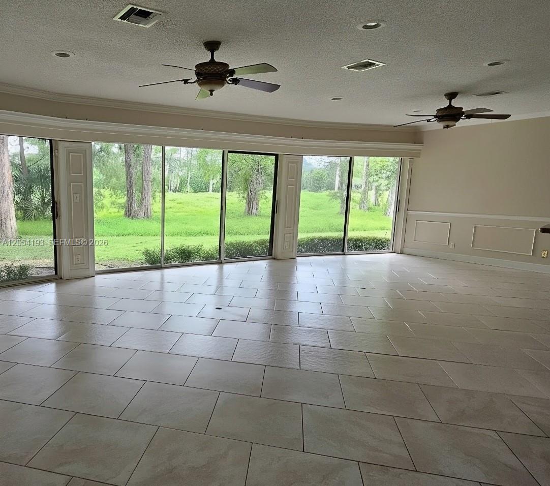 A spacious room features light tile flooring, two ceiling fans, and large sliding glass doors — 4602 King Palm Dr, Tamarac FL 33319, TAMARAC, FL