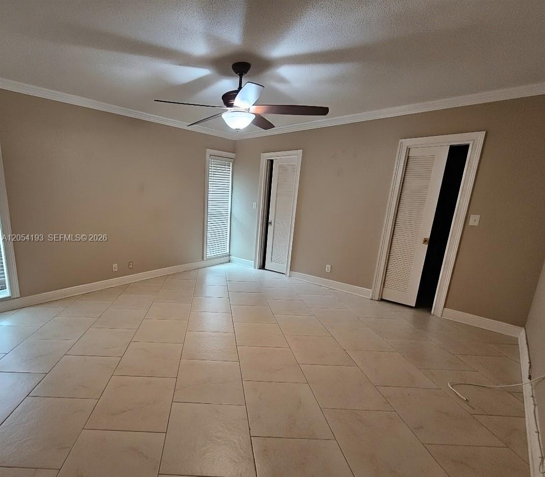 An empty room features beige walls, light-colored tile flooring, a ceiling fan, and two louvered doors — 4602 King Palm Dr, Tamarac FL 33319, TAMARAC, FL