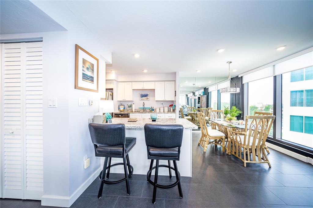 A kitchen with a granite island, bar stools, and an adjacent dining area with windows — 707 S GULFSTREAM AVENUE UNIT 602, SARASOTA, FL