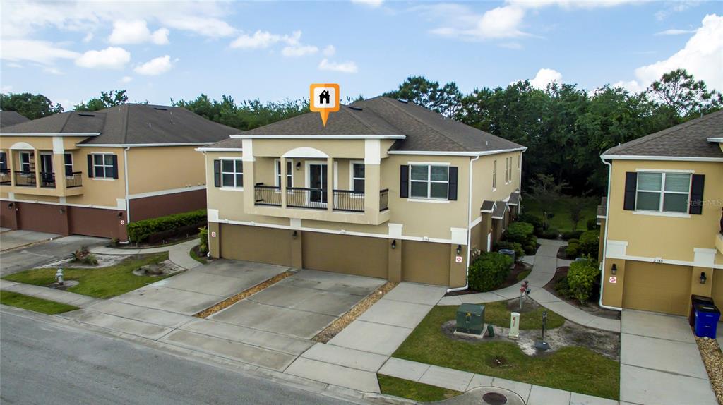 An exterior view of a two-story townhouse with a balcony and three garage doors — 2148 BETSY ROSS LANE UNIT 2148, ST CLOUD, FL