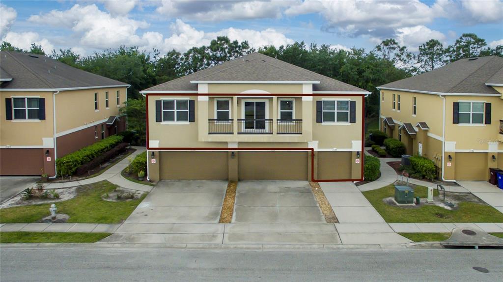 An exterior view of a two-story townhouse with a three-car garage and a balcony — 2148 BETSY ROSS LANE UNIT 2148, ST CLOUD, FL