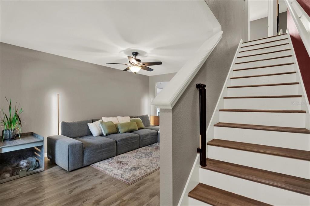 A living room with a grey sectional sofa and a staircase with wooden treads — 3017 MOJAVE OAK DRIVE, VALRICO, FL