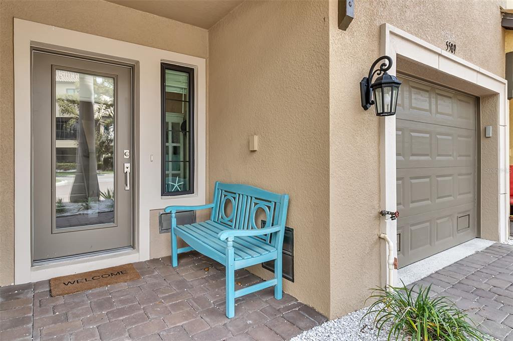 A front entryway features a light blue bench, a glass-paneled door, and a garage door — 5589 CANNES CIRCLE UNIT 4-102, SARASOTA, FL