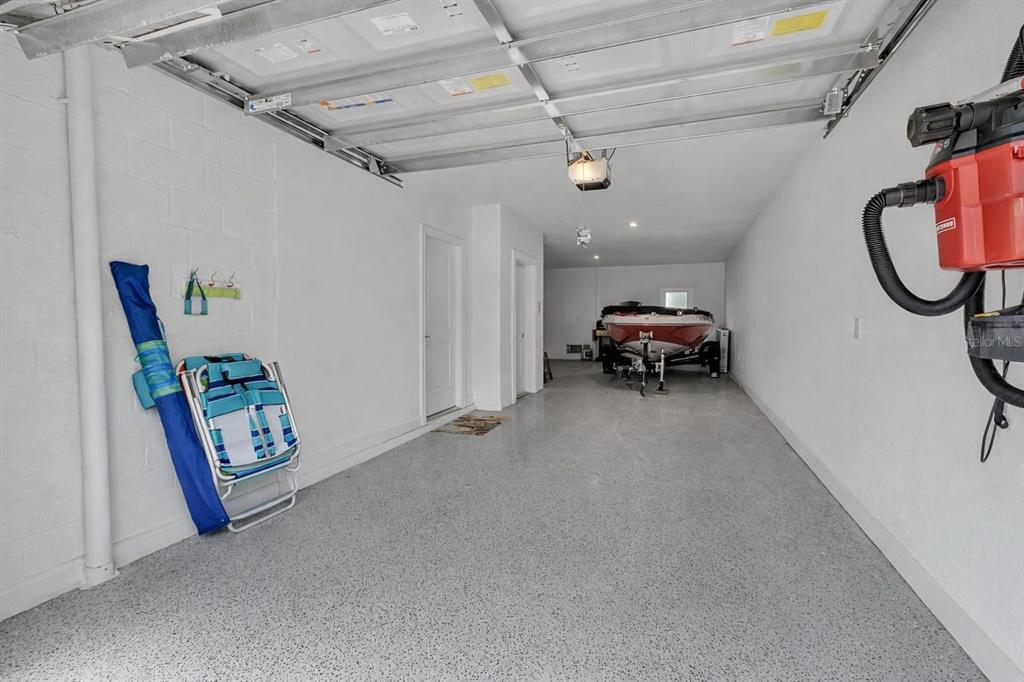A garage with white walls, a speckled epoxy floor, and a boat parked inside — 5589 CANNES CIRCLE UNIT 4-102, SARASOTA, FL