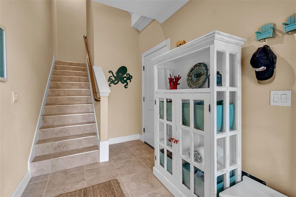 A tiled entryway features a staircase with a wooden handrail and a white display cabinet — 5589 CANNES CIRCLE UNIT 4-102, SARASOTA, FL
