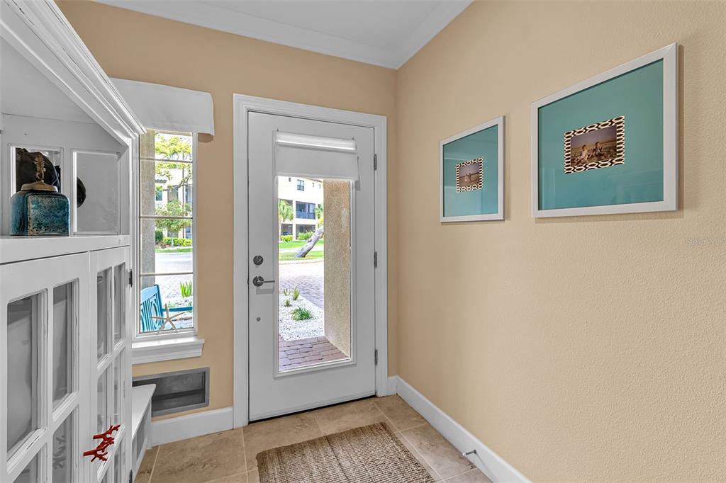 An entryway features a white door, beige walls, tiled floors, and two framed wall pictures — 5589 CANNES CIRCLE UNIT 4-102, SARASOTA, FL