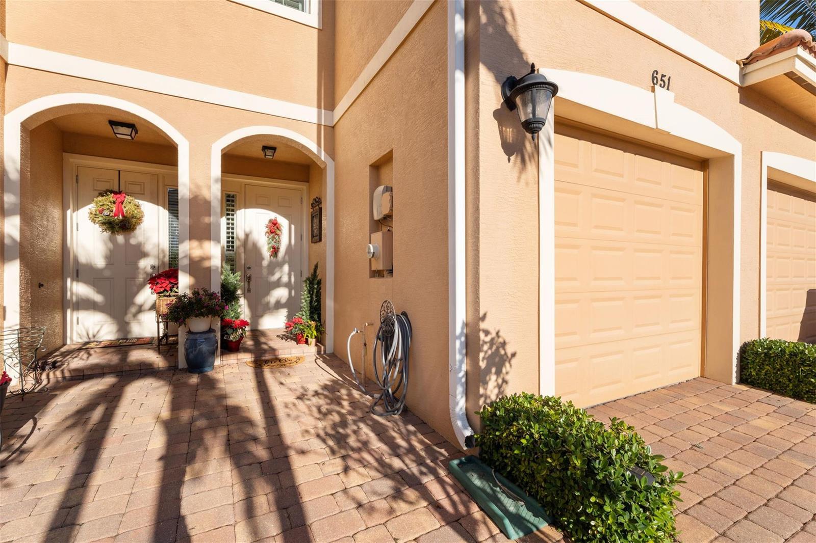 The exterior of a tan stucco home features a paved driveway, a garage, and arched entryways — 651 SW Glen Crest Way # 2, Stuart FL 34997, STUART, FL