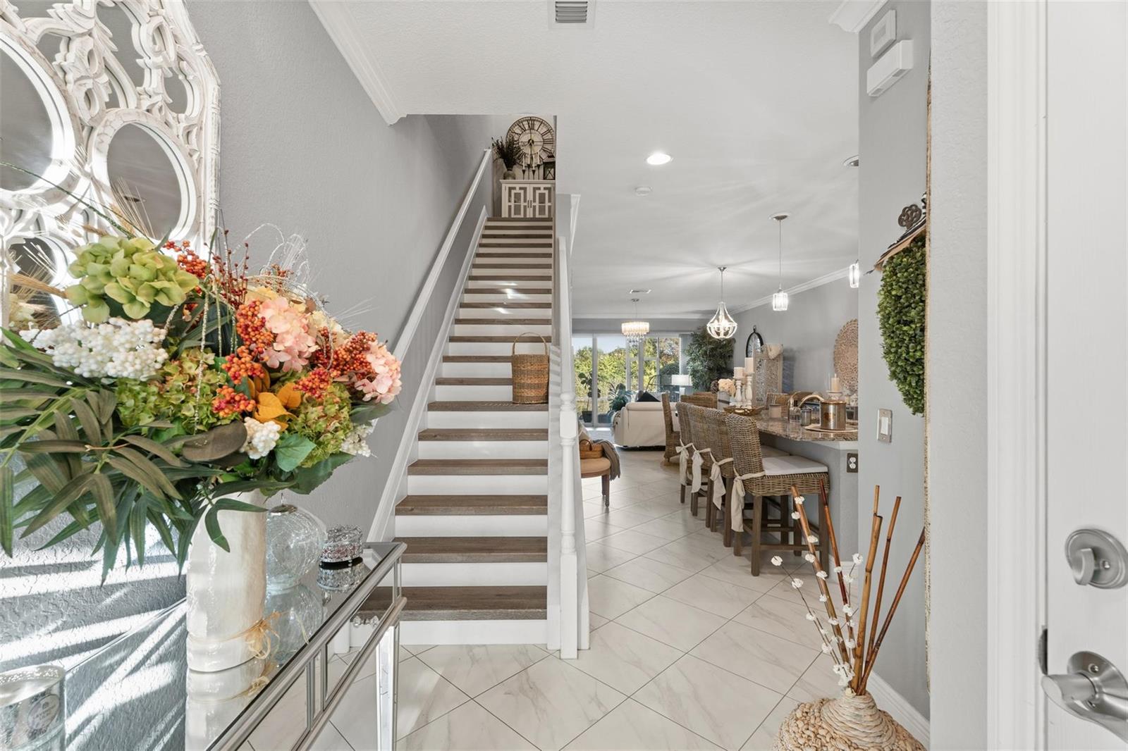 An entryway features a staircase, a mirrored console table, and a view into the kitchen — 651 SW Glen Crest Way # 2, Stuart FL 34997, STUART, FL