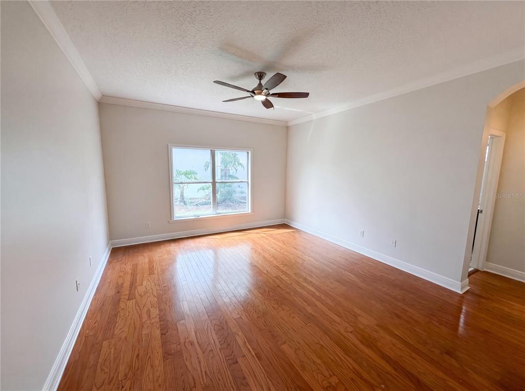 An empty bedroom features hardwood floors, a ceiling fan, and a window with outdoor views — 3379 MORELYN CREST CIRCLE, ORLANDO, FL