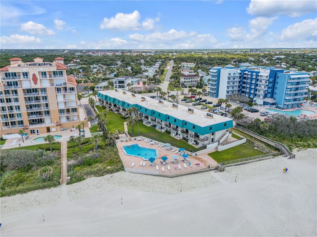 An aerial view shows a beachside resort complex with pools, balconies, and surrounding residential areas — 701 S ATLANTIC AVENUE UNIT UT10, NEW SMYRNA BEACH, FL