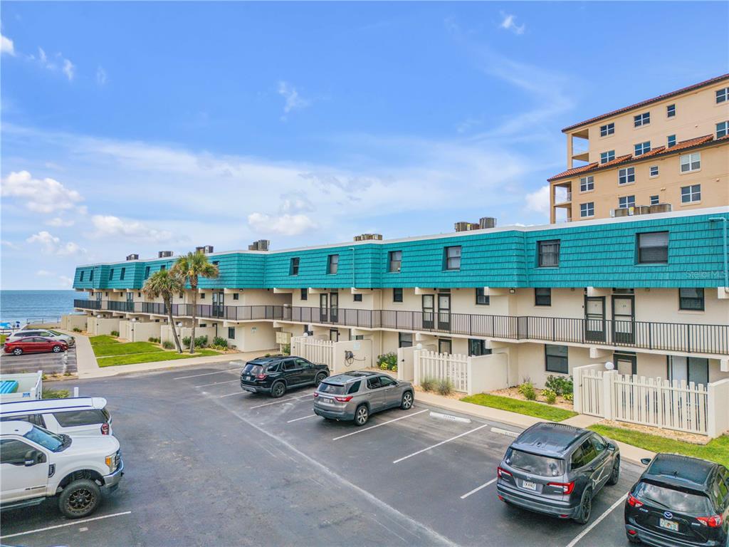An exterior view of a multi-story residential building with a teal roof near the ocean — 701 S ATLANTIC AVENUE UNIT UT10, NEW SMYRNA BEACH, FL