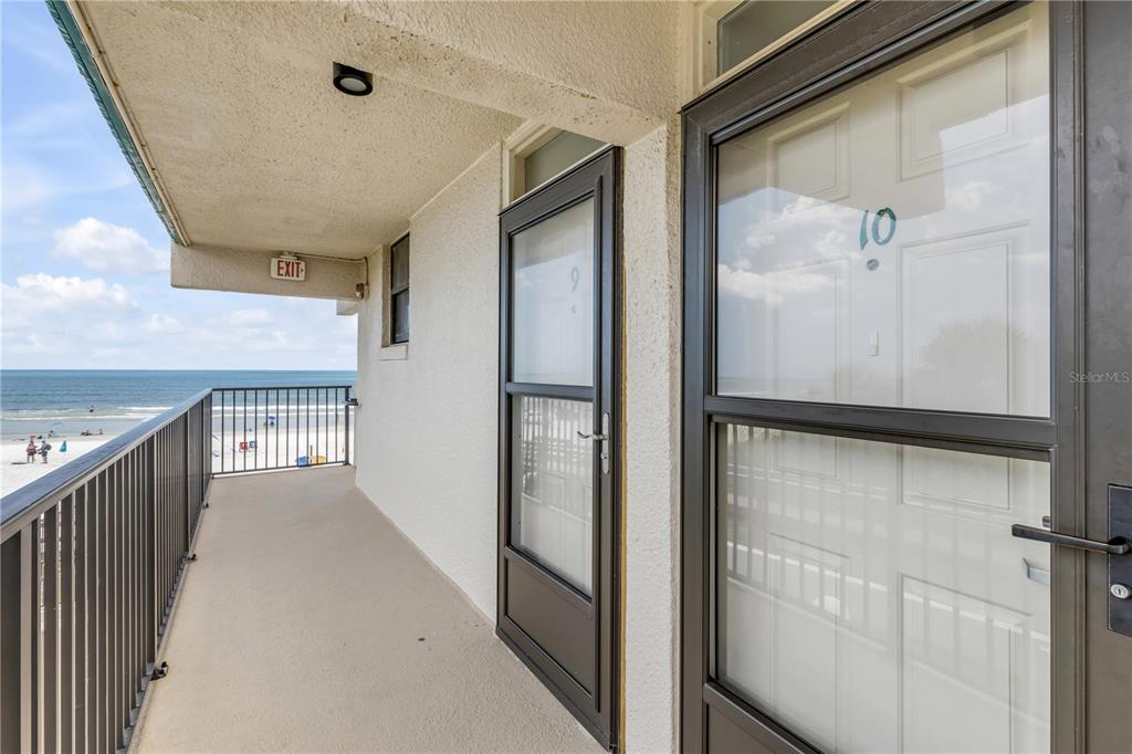 An exterior balcony overlooks the beach with two numbered doors and an exit sign — 701 S ATLANTIC AVENUE UNIT UT10, NEW SMYRNA BEACH, FL
