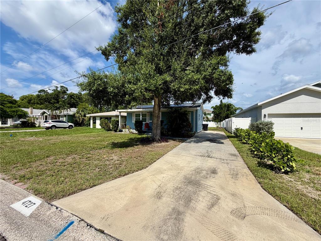 A blue house with a large tree and a concrete driveway under a cloudy sky — 4727 20TH STREET N, ST PETERSBURG, FL