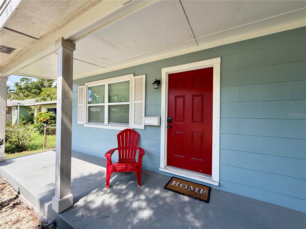 A blue house exterior features a red front door, a red chair, and a porch — 4727 20TH STREET N, ST PETERSBURG, FL