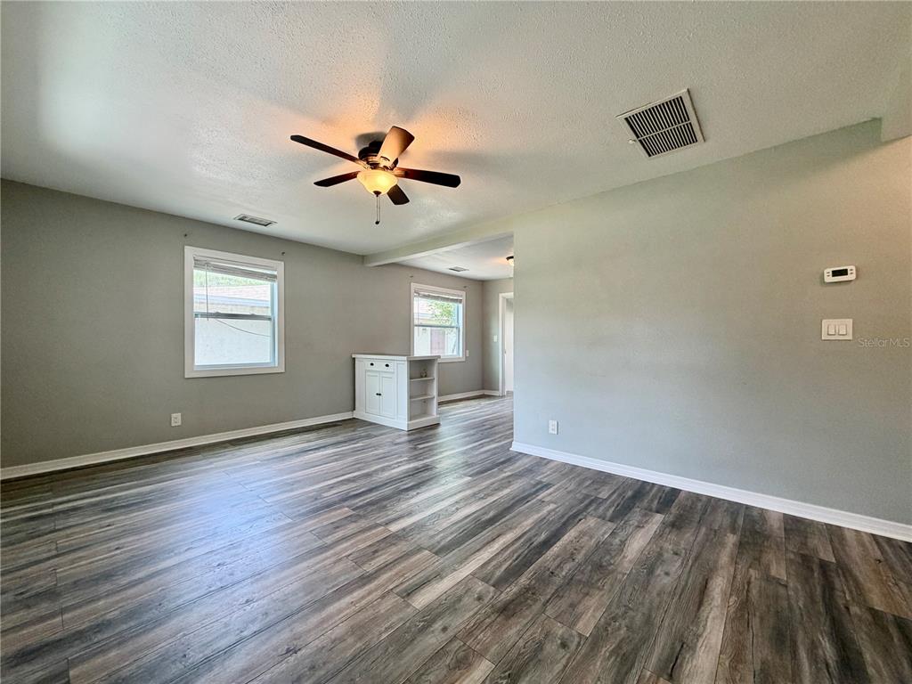 An empty living room features gray walls, wood-look laminate flooring, and a ceiling fan — 4727 20TH STREET N, ST PETERSBURG, FL