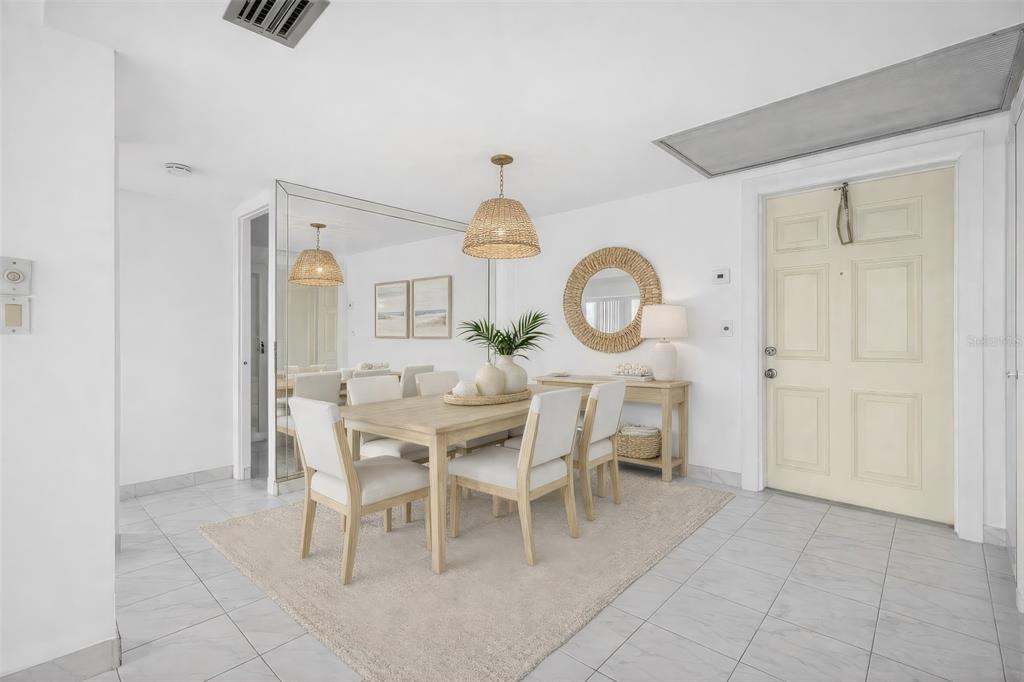 A dining room features a wooden table, white chairs, a woven pendant light, and mirrors — 1820 NEW PALM WAY UNIT 306, BOYNTON BEACH, FL