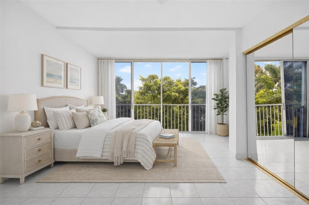A bright bedroom features a bed, tiled floors, and a balcony with lush green views — 1820 NEW PALM WAY UNIT 306, BOYNTON BEACH, FL