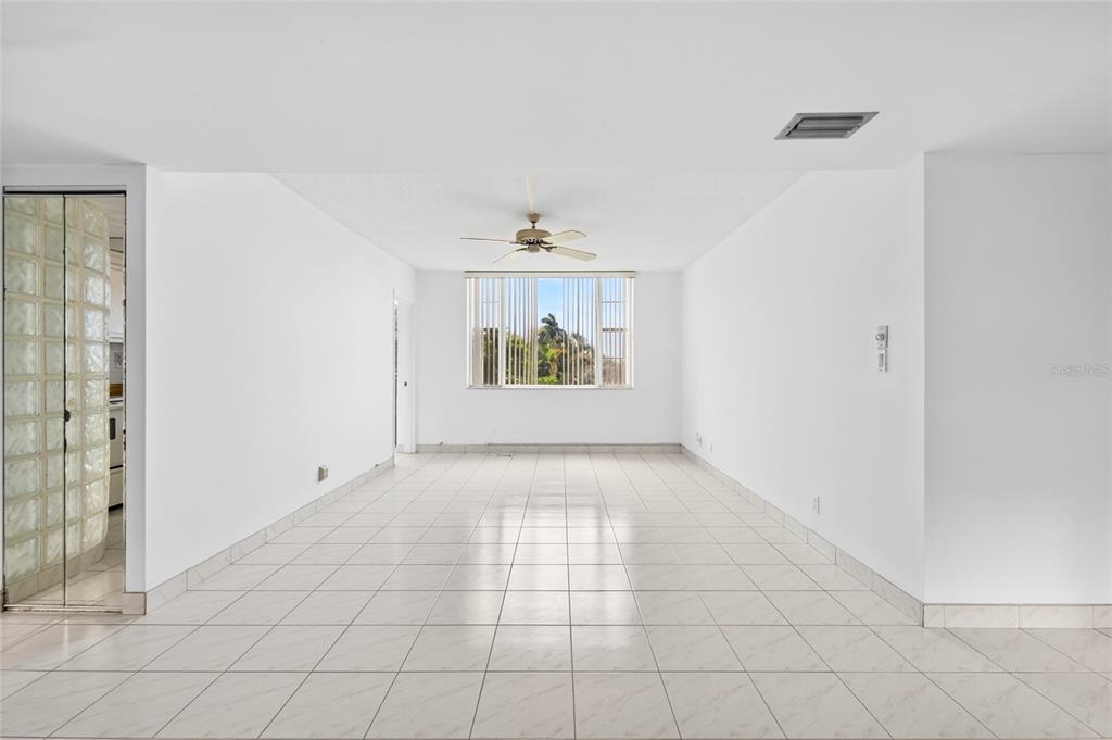A bright, empty room features white tile floors, white walls, and a ceiling fan — 1820 NEW PALM WAY UNIT 306, BOYNTON BEACH, FL