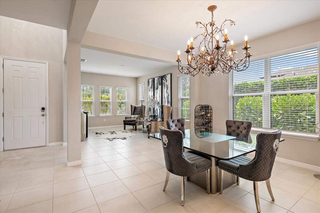 A dining area with a glass table, tufted chairs, and a chandelier sits near an entryway — 9085 LUNA LANE, SARASOTA, FL