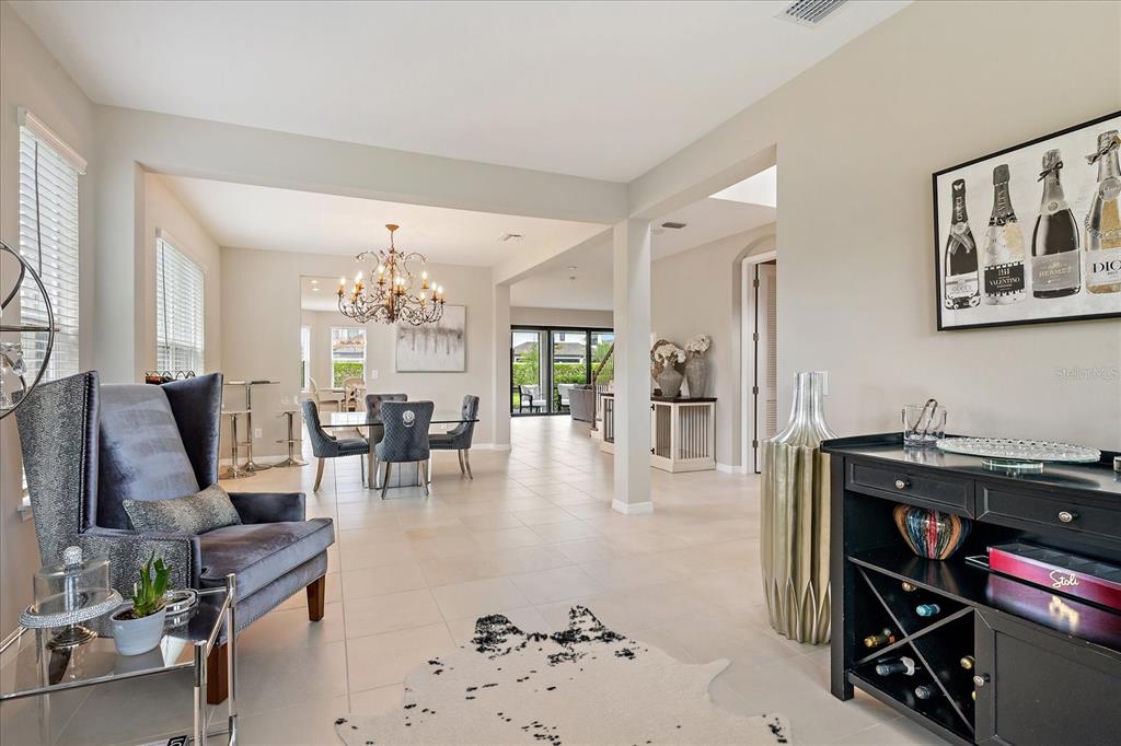 A living and dining area features tile floors, a chandelier, and a dark wood bar — 9085 LUNA LANE, SARASOTA, FL