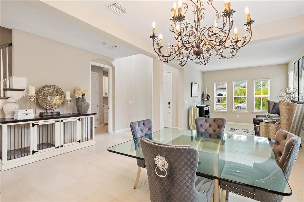 A dining room features a glass table, tufted chairs, and a large ornate chandelier — 9085 LUNA LANE, SARASOTA, FL