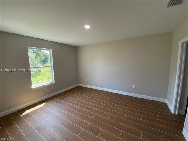 An empty bedroom features light-colored walls, wood-look tile flooring, and a single window — 117-119 Meadow, Lehigh Acres FL 33973, LEHIGH ACRES, FL