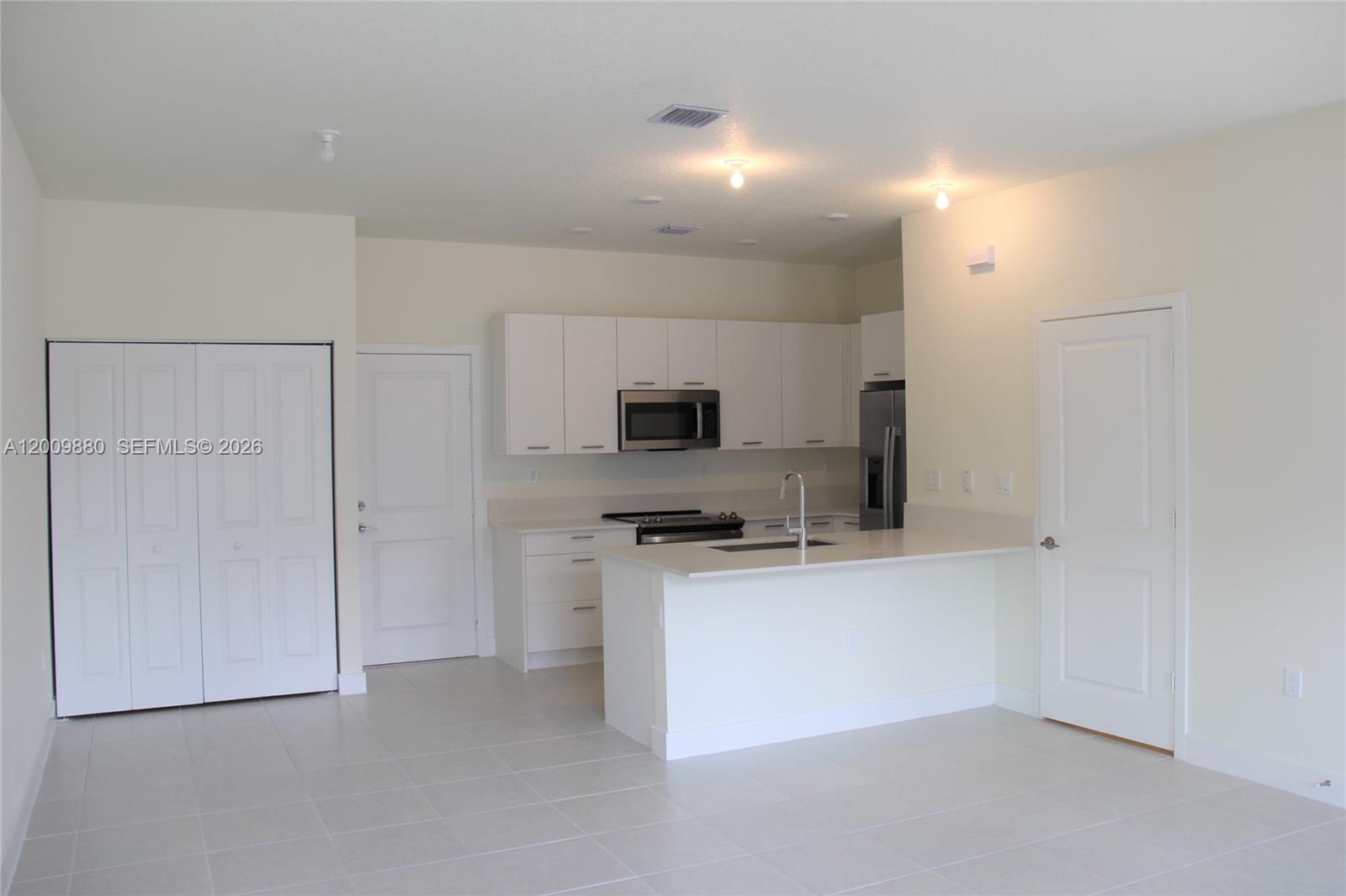 A kitchen features white cabinets, stainless steel appliances, a peninsula, and light-colored tile flooring — 4272 NW 82nd Ave # 4272, Doral FL 33166, DORAL, FL