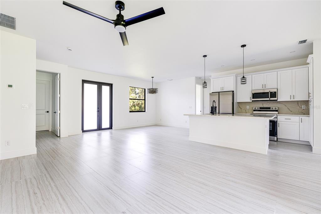 A bright, open-concept kitchen and living area features white cabinetry, tile flooring, and a ceiling fan — 17196 GLENVIEW AVENUE, PORT CHARLOTTE, FL