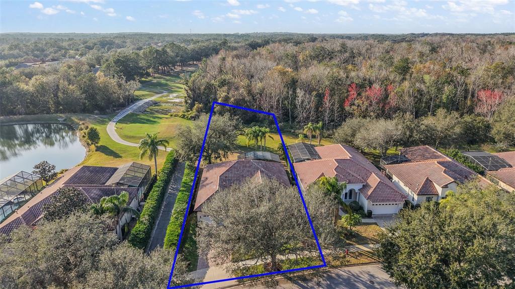 An aerial view shows a residential house with a tiled roof and a large tree — 9930 SANTA BARBARA COURT, HOWEY IN THE HILLS, FL