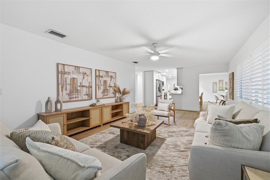 A bright living room features a light-colored sofa, wooden media console, and a coffee table — 1931 ARVIS CIRCLE E, CLEARWATER, FL