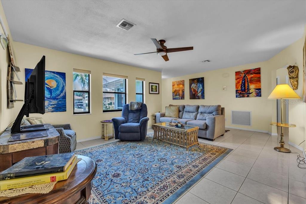 A living room features tile floors, a blue area rug, a sofa, and a recliner — 6150 AVILA STREET, ENGLEWOOD, FL