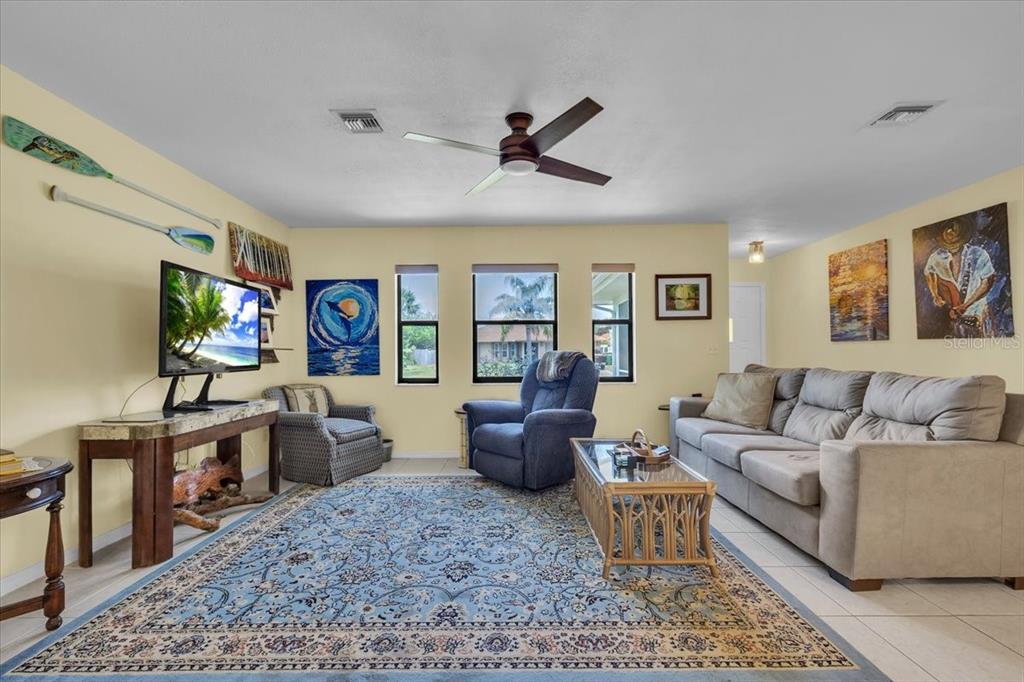 A living room features a blue area rug, a beige sofa, and a recliner — 6150 AVILA STREET, ENGLEWOOD, FL