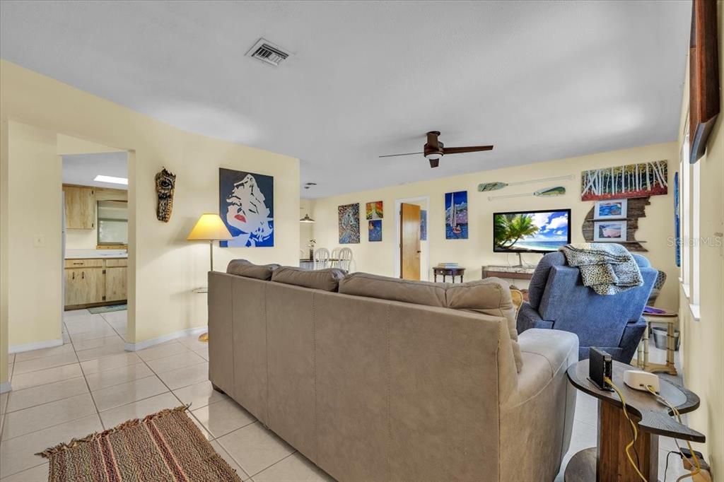 A living room features a beige sofa, a blue recliner, tile flooring, and wall art — 6150 AVILA STREET, ENGLEWOOD, FL