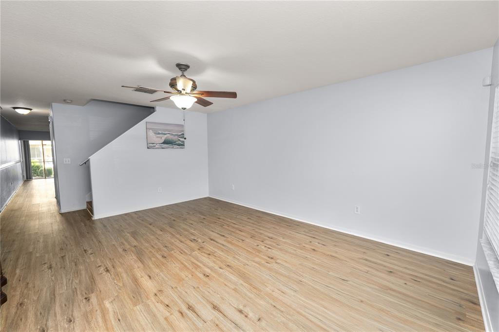 An empty living room features light-colored walls, wood-look flooring, and a ceiling fan — 5455 LIMESTONE LANE, LAKELAND, FL