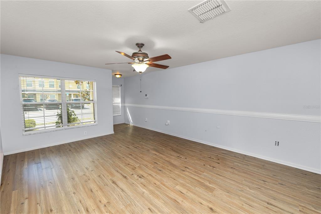 An empty living room features light blue walls, wood-look flooring, and a ceiling fan — 5455 LIMESTONE LANE, LAKELAND, FL