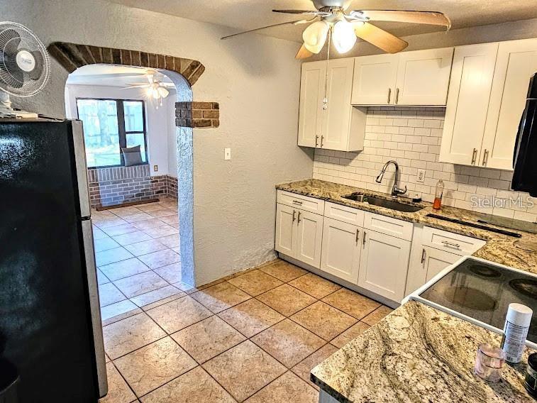 A kitchen features white cabinets, granite countertops, a subway tile backsplash, and a tiled floor — 6801 79TH AVENUE N, PINELLAS PARK, FL