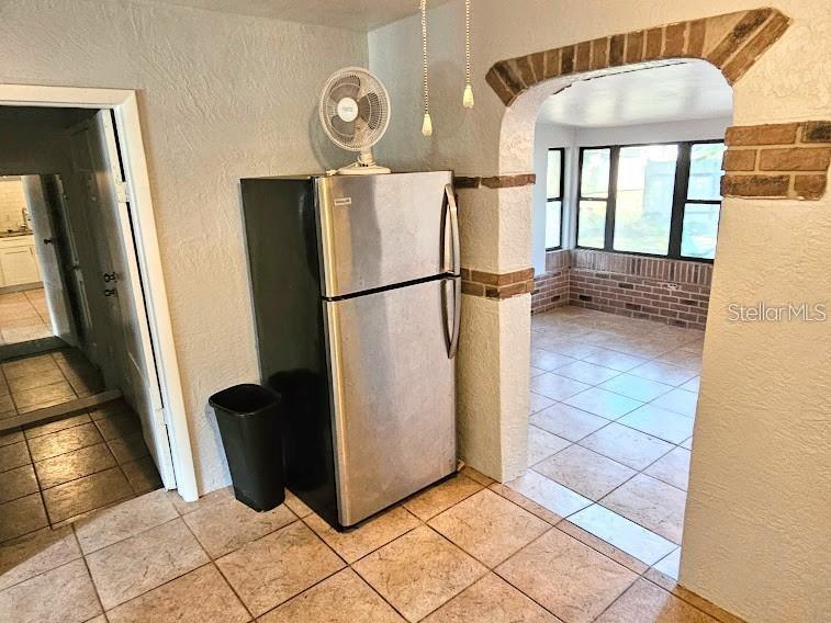 A stainless steel refrigerator stands in a tiled kitchen next to an arched brick doorway — 6801 79TH AVENUE N, PINELLAS PARK, FL