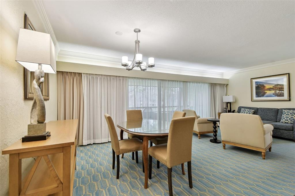 A dining area with a glass table and chairs sits in front of a living room — 36750 US 19 N UNIT 06211, PALM HARBOR, FL