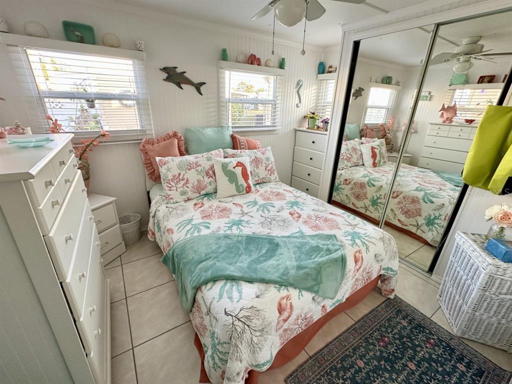 A coastal-themed bedroom features a bed with patterned bedding, white furniture, and mirrored closet doors — 2094 DETROITER STREET, SARASOTA, FL