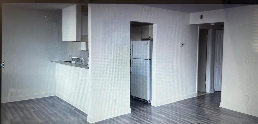 A kitchen with a breakfast bar, white refrigerator, and gray wood-look flooring — 900 S PENINSULA DRIVE UNIT 111, DAYTONA BEACH, FL