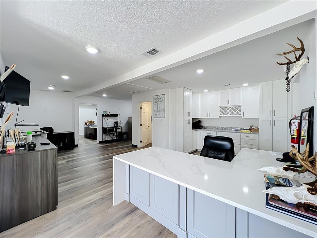 A modern office space features a large white-topped desk, grey cabinetry, and wood-look flooring — 180 S RONALD REAGAN BOULEVARD UNIT 112, LONGWOOD, FL